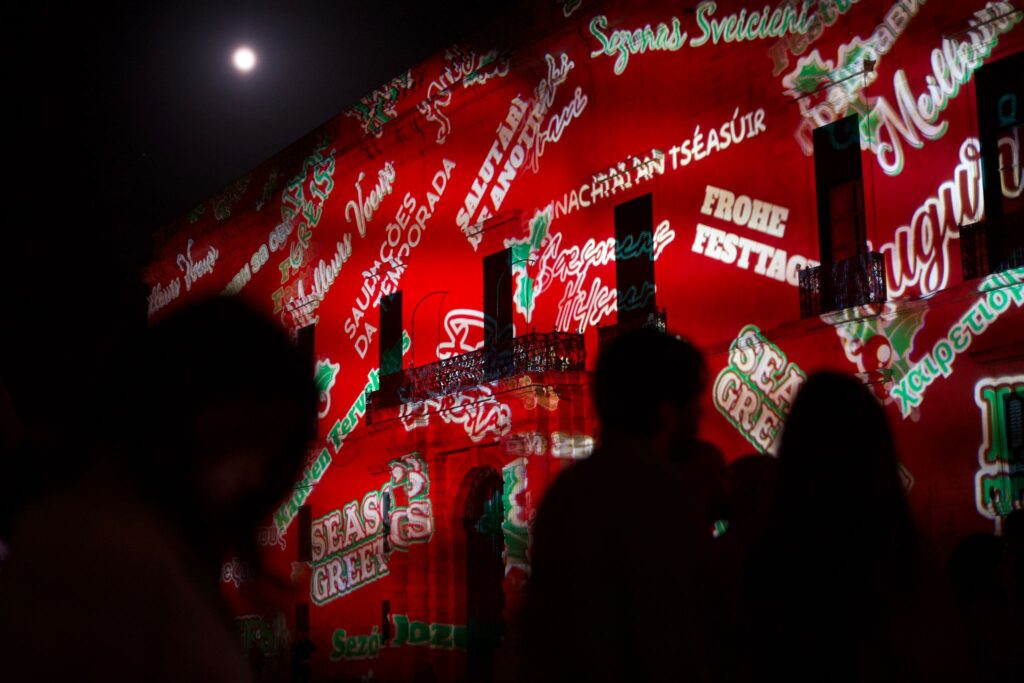 A photo of passersby watching Christmas projections in St George's Square Valletta