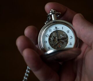 A photo of a hand-held clock showing the time
