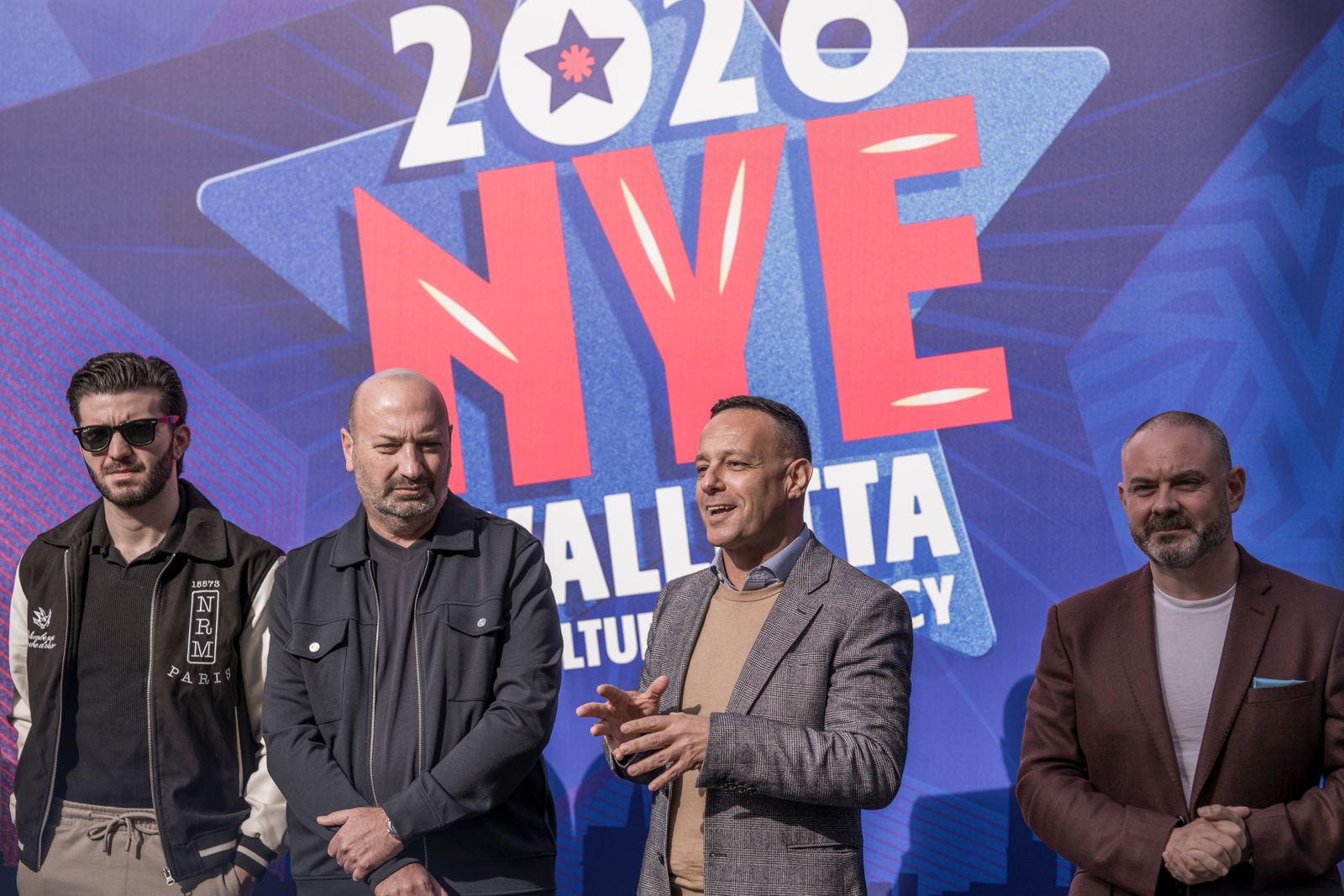 A photo showing Valletta Cultural Agency Chairman Jason Micallef, together with the Minister for Culture, Lands and Local Government Owen Bonnici and distinguished guests addressing a press conference in front of a backdrop that reads 2026 NYE Valletta