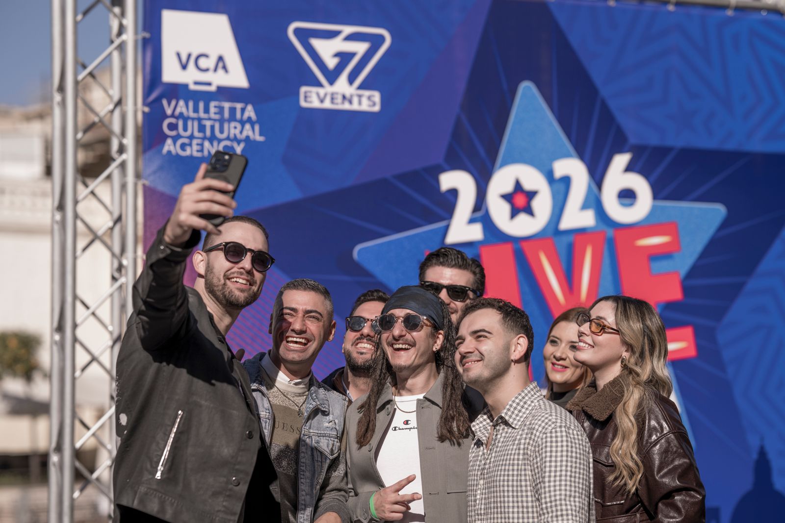 A number of Maltese entertainers taking a selfie with the 2026 NYE Valletta backdrop
